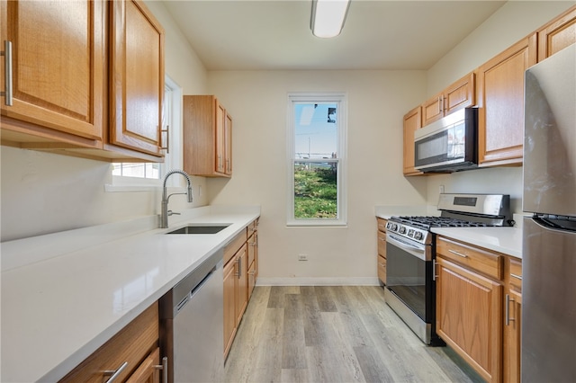 kitchen featuring light wood-type flooring, stainless steel appliances, sink, and plenty of natural light