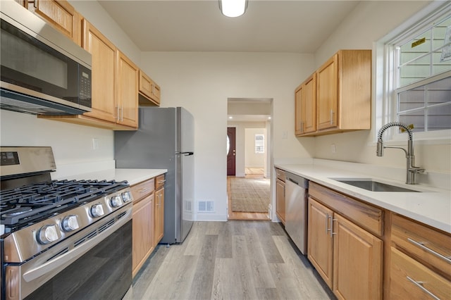 kitchen featuring appliances with stainless steel finishes, sink, and light hardwood / wood-style floors