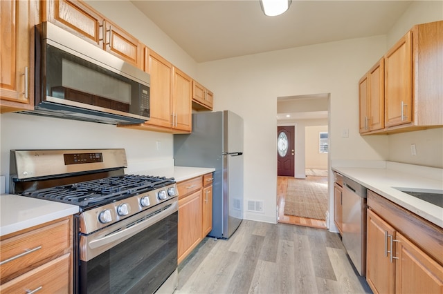 kitchen with light brown cabinets, stainless steel appliances, and light hardwood / wood-style floors