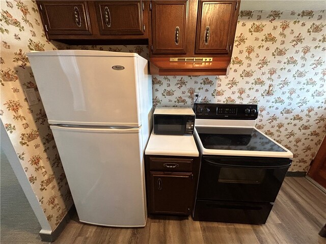 kitchen featuring white fridge, hardwood / wood-style flooring, electric range oven, and custom range hood