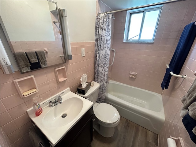 full bathroom with wood-type flooring, shower / bath combination with curtain, toilet, tile walls, and vanity