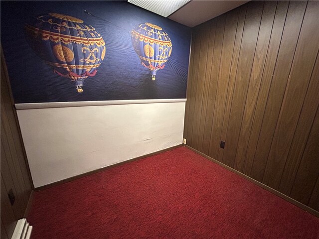 empty room featuring carpet and wooden walls