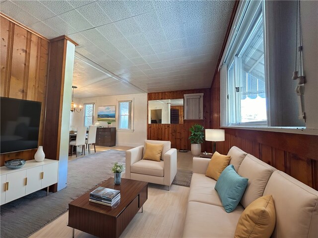 living room with wood walls, hardwood / wood-style flooring, and a chandelier