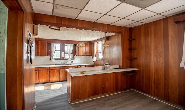 kitchen featuring kitchen peninsula, pendant lighting, dark hardwood / wood-style floors, and wood walls