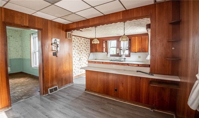 kitchen with wood walls, wood-type flooring, decorative light fixtures, and kitchen peninsula