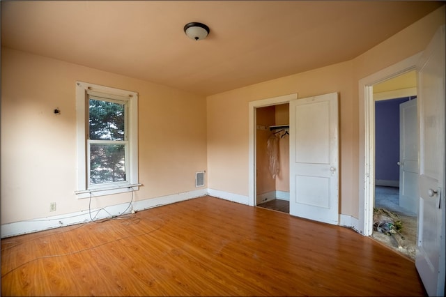 unfurnished bedroom with a closet, a spacious closet, and hardwood / wood-style floors