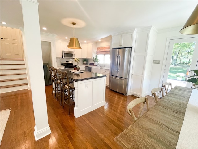 kitchen featuring a kitchen breakfast bar, white cabinetry, stainless steel appliances, and dark hardwood / wood-style floors