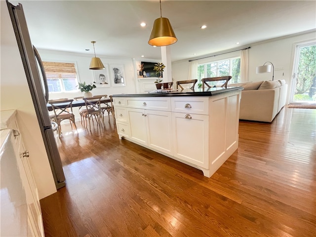 kitchen featuring a kitchen island, white cabinetry, stainless steel refrigerator, dark hardwood / wood-style floors, and pendant lighting