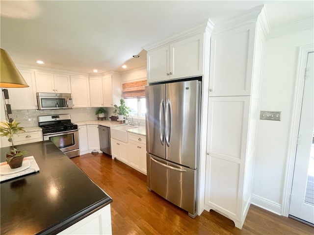 kitchen featuring sink, white cabinets, dark hardwood / wood-style flooring, appliances with stainless steel finishes, and tasteful backsplash