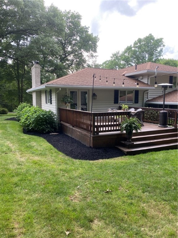 back of property with a deck and a lawn