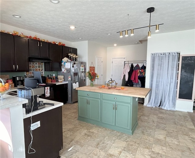 kitchen with stainless steel refrigerator with ice dispenser, a textured ceiling, decorative light fixtures, and a kitchen island