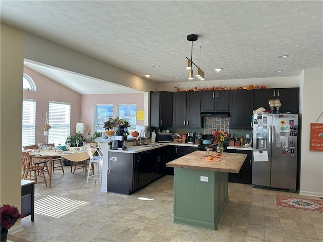 kitchen featuring butcher block counters, sink, stainless steel fridge, pendant lighting, and a kitchen island