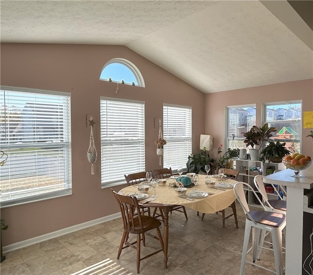 dining room with a textured ceiling and lofted ceiling