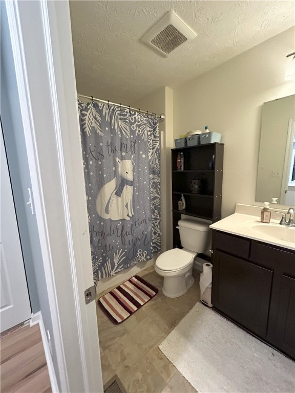 bathroom featuring a textured ceiling, vanity, toilet, and walk in shower