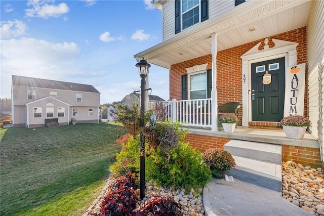 entrance to property featuring a lawn and a porch