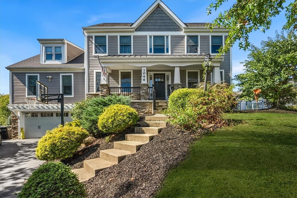 view of front of house with a front yard, a garage, and a porch