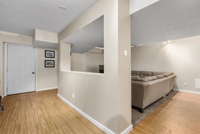 hallway with a textured ceiling and hardwood / wood-style flooring