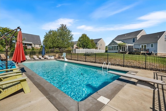 view of pool with a patio, a lawn, and a diving board