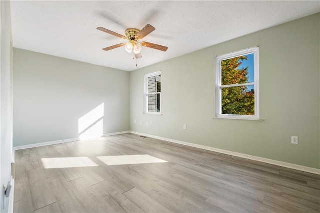 empty room with a textured ceiling, light wood-type flooring, and ceiling fan