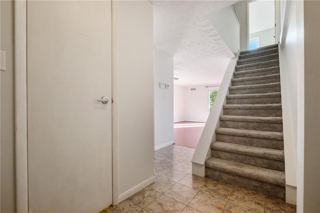 stairs with a textured ceiling and tile patterned flooring