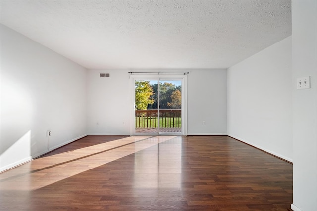 spare room featuring a textured ceiling and dark hardwood / wood-style floors