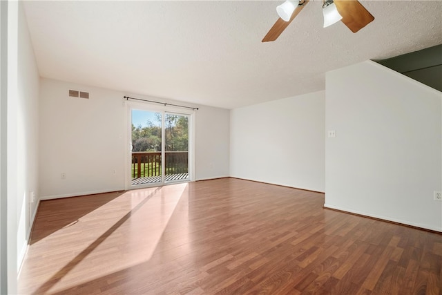 empty room with ceiling fan, wood-type flooring, and a textured ceiling