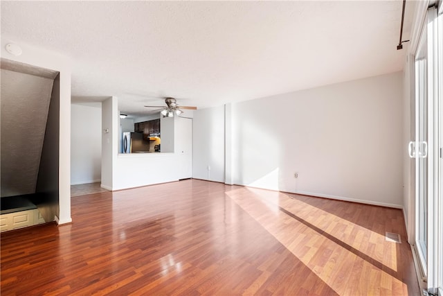 unfurnished living room with ceiling fan, hardwood / wood-style flooring, and a textured ceiling