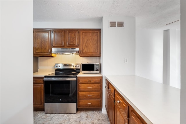 kitchen with backsplash, stainless steel appliances, a textured ceiling, and light tile patterned floors