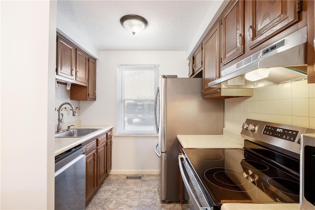 kitchen featuring light tile patterned floors, appliances with stainless steel finishes, backsplash, a textured ceiling, and sink