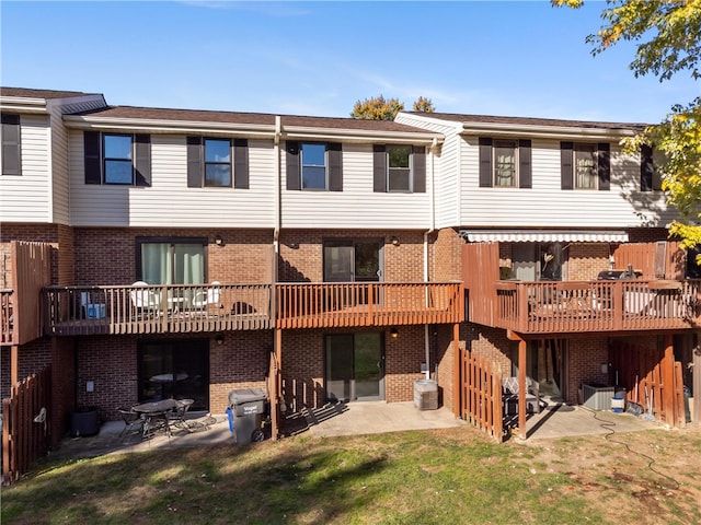 rear view of property featuring a patio, a deck, central AC unit, and a lawn