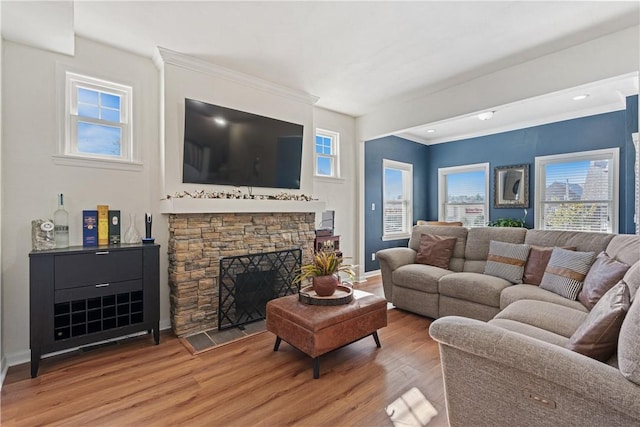 living room featuring a stone fireplace, crown molding, and wood-type flooring