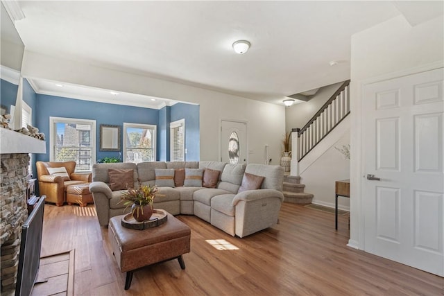 living room featuring a stone fireplace, crown molding, and hardwood / wood-style floors