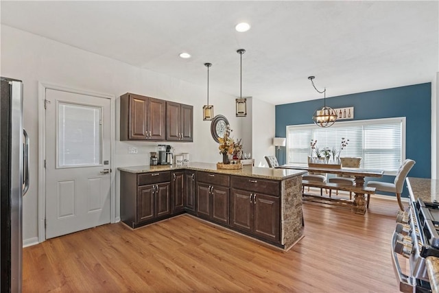 kitchen featuring kitchen peninsula, pendant lighting, light hardwood / wood-style floors, and stainless steel refrigerator