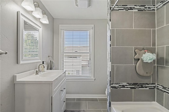 bathroom featuring tile patterned floors, vanity, a healthy amount of sunlight, and a tile shower