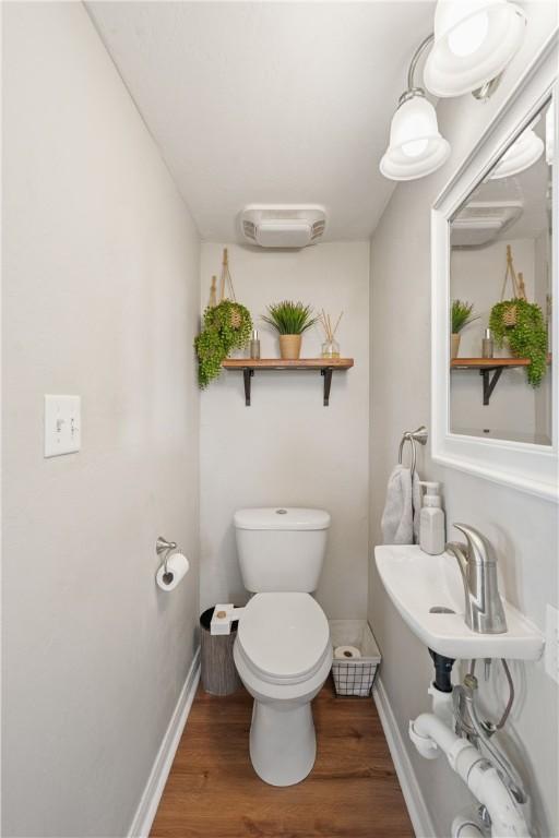 bathroom featuring toilet, hardwood / wood-style floors, and a wall unit AC