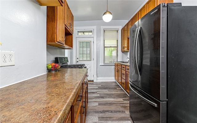 kitchen with sink, appliances with stainless steel finishes, pendant lighting, and dark hardwood / wood-style flooring