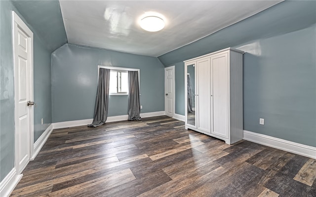 unfurnished bedroom featuring lofted ceiling and dark hardwood / wood-style floors