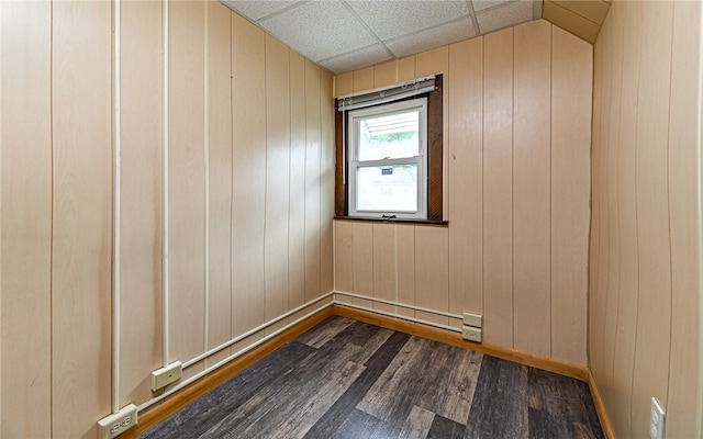 empty room with wood walls and dark hardwood / wood-style flooring