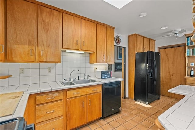 kitchen with tile counters, sink, black appliances, light tile patterned flooring, and tasteful backsplash