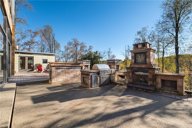 view of patio / terrace with area for grilling, a wooden deck, and an outdoor fireplace