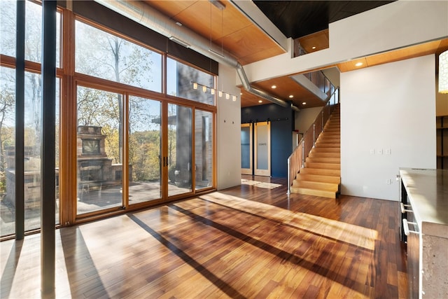 interior space with hardwood / wood-style floors, a towering ceiling, and floor to ceiling windows