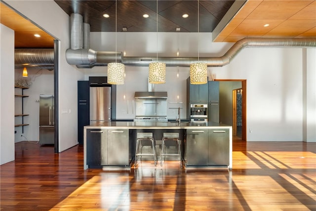 kitchen featuring sink, green cabinets, pendant lighting, hardwood / wood-style flooring, and stainless steel refrigerator