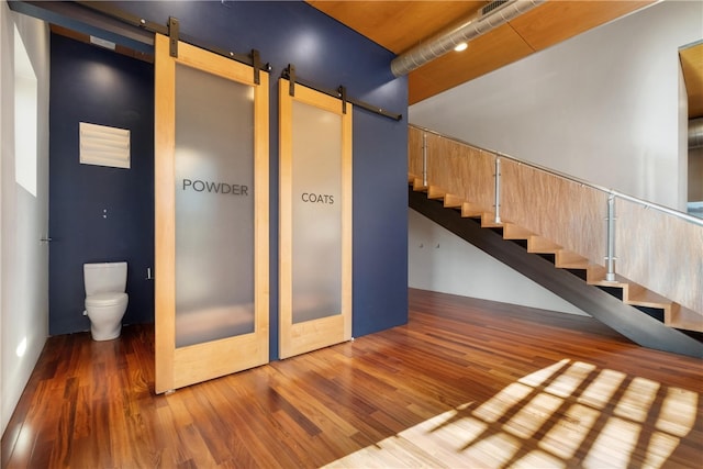 staircase featuring a barn door and hardwood / wood-style flooring