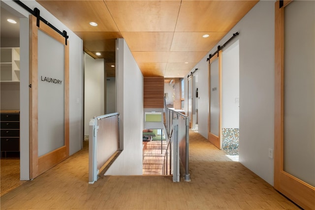 hallway featuring a barn door and light hardwood / wood-style floors