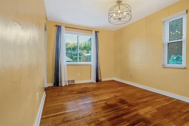 spare room with a notable chandelier and hardwood / wood-style flooring