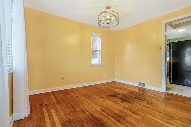 spare room with light hardwood / wood-style flooring and a chandelier