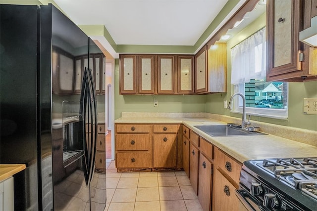 kitchen with light tile patterned floors, extractor fan, sink, and black fridge