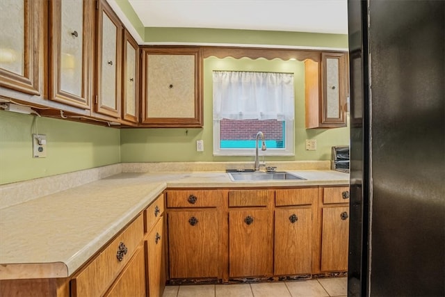 kitchen featuring light tile patterned flooring, sink, and black refrigerator