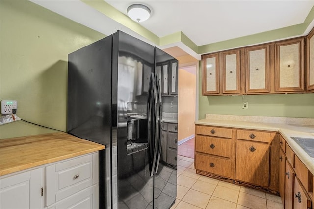 kitchen with white cabinets, black refrigerator with ice dispenser, and light tile patterned floors