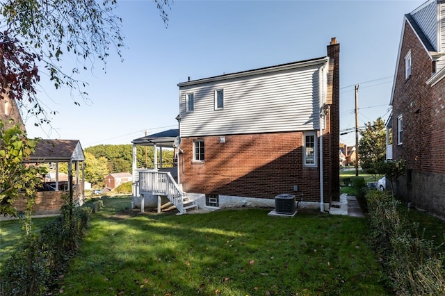 rear view of property featuring central AC and a lawn